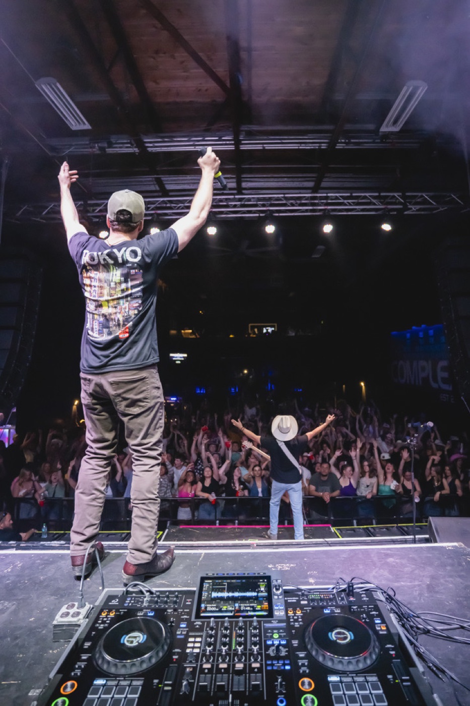 Mixmode on stage at The Complex in Salt Lake City with arms raised over the decks